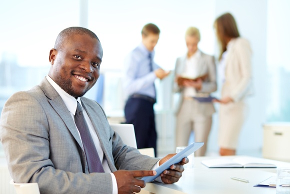 Portrait of happy leader with touchpad looking at camera in work